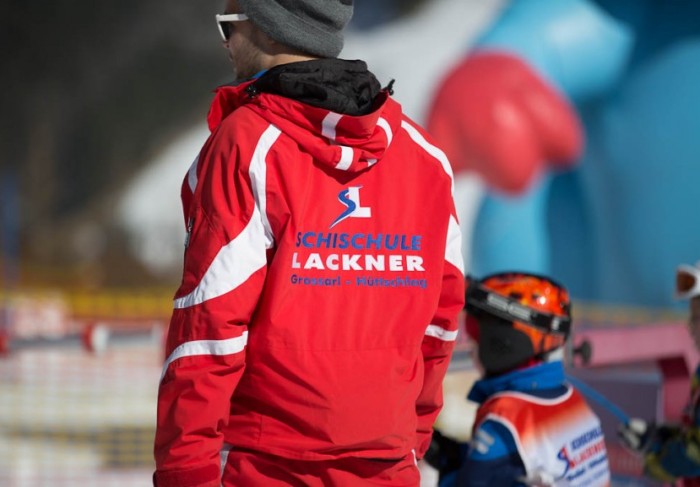 Skilehrer mit Skischul-Logo auf der Skijacke